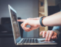 Two people pointing at a laptop screen analyzing the results of a parallel coordinate plot.